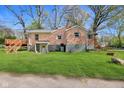 Exterior backyard view of brick home with lush green grass and deck area, offering outdoor space at 7002 N Ralston Ave, Indianapolis, IN 46220