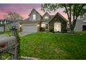 Charming two-story home with a brick facade, manicured lawn, and attached two-car garage at dusk at 8875 White Fir Dr, Indianapolis, IN 46256