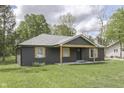Charming one-story home with dark siding, wood accents, covered porch, and a well-manicured front lawn at 1301 Stafford Rd, Plainfield, IN 46168