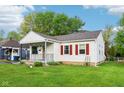 Quaint home with charming details like red shutters, covered porch, and lush lawn, creating a welcoming facade at 473 N 17Th St, Noblesville, IN 46060