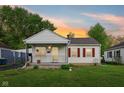 Charming home featuring white siding, red shutters, a cozy front porch, and well-maintained landscaping at sunset at 473 N 17Th St, Noblesville, IN 46060