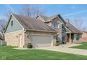 A charming home featuring a two-car garage, brick accents, and fresh green lawn on a sunny day at 4940 Sundance Trl, Indianapolis, IN 46239