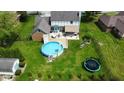 Aerial view of a backyard with a pool, deck, patio, and trampoline in the fenced yard at 562 Covered Bridge Rd, Greenwood, IN 46142