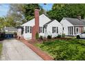 Quaint home with a brick pathway, lush green lawn, and mature trees under a bright blue sky at 5938 Haverford Ave, Indianapolis, IN 46220