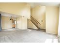 Spacious living room featuring neutral carpeting, vaulted ceiling, and staircase at 6472 Creekshore Ln, Indianapolis, IN 46268