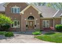 Elegant front entrance with brick facade, arched doorway, and well-maintained landscaping at 923 Woodcrest Way, Anderson, IN 46012