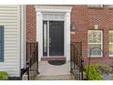 A stately front door with black hardware is framed by brick and a classic white trim at 9417 Glencroft Way, Indianapolis, IN 46250