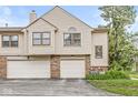 Charming townhouse featuring a two-car garage, neutral siding and a well-maintained brick facade at 9553 Maple Way, Indianapolis, IN 46268
