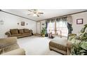 Inviting living room with neutral carpet, a ceiling fan, comfortable seating, and a large bright window at 9660 Old Haggard Rd, Morgantown, IN 46160