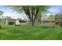 Expansive backyard featuring lush green lawn, mature trees, and storage sheds at 1402 Arcola Ct, Beech Grove, IN 46107