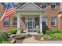 Inviting front porch with white columns, decorated with flowers and a cozy chair at 14162 Nicholas Dr, Carmel, IN 46074
