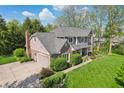 Aerial view of a two-story home with an attached garage, lovely landscaping, and a large green lawn at 1508 Redwood Dr, Carmel, IN 46032