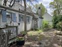 The back of the house shows weathered siding, overgrown vegetation, and a dilapidated deck at 2517 Baur Dr, Indianapolis, IN 46220