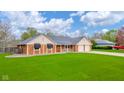 Beautiful brick home with a lush green lawn, black awnings and attached two-car garage at 310 Edgewood E Pl, Anderson, IN 46011