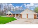 Inviting brick home with covered porch and two-car garage on a manicured lawn at 310 Edgewood E Pl, Anderson, IN 46011