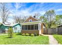 A charming home boasts a screened-in porch and a well-manicured front yard with lush green grass at 4623 Evanston Ave, Indianapolis, IN 46205