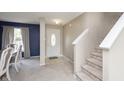 Bright foyer with staircase and neutral carpet leading to a dining room with modern gray accents at 8709 Orchard Grove Ln, Camby, IN 46113