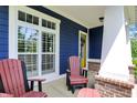 Inviting porch with a seating area, white columns, brick accents, and a bright yellow front door at 1404 Rosebank Dr, Westfield, IN 46074
