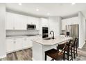 Bright kitchen with an island bar, stainless steel appliances, sleek quartz countertops, and a wooden floor at 16693 Churning Way, Noblesville, IN 46060