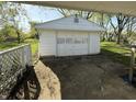 View of a detached single-car garage with a white exterior and classic detailing, accessible via a cracked driveway at 1716 Arlene Dr, Indianapolis, IN 46219