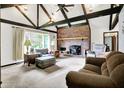 Inviting living room with vaulted ceilings, exposed beams, large windows, and a cozy brick fireplace at 3154 E German E Rd, Shelbyville, IN 46176