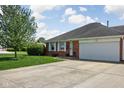 Red brick home featuring an attached garage, white trim, and a beautiful green lawn with mature landscaping at 389 Vinewood N Dr, Brownsburg, IN 46112