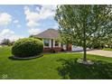 Well-manicured lawn with mature tree and green bush, leading to a brick home with an attached garage at 389 Vinewood N Dr, Brownsburg, IN 46112