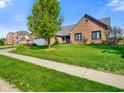 Attractive brick home showcasing a well-maintained lawn and a mature tree, complemented by a paved walkway at 4316 Moss Ridge Cir, Indianapolis, IN 46237