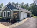 View of the exterior showing the garage and landscaped grounds with a dog statue at 5607 E 500 N, Greenfield, IN 46140