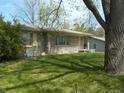 Attractive stone-clad single-story house with mature tree and landscaped yard, offering a classic and cozy curb appeal at 6736 E Michigan St, Indianapolis, IN 46219
