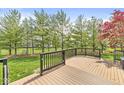 A wooden back deck overlooks a spacious, green backyard lined with mature trees and fencing at 6758 Woodcliff Cir, Zionsville, IN 46077
