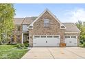 Detailed front view of a brick house showing the driveway, garage doors, and the front facade at 6758 Woodcliff Cir, Zionsville, IN 46077