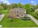 Stunning aerial view of a well-kept brick home with a large yard, mature trees, and basketball court at 960 Arrowwood Dr, Carmel, IN 46033