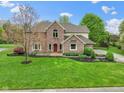 Beautifully landscaped two-story brick home with a basketball court, mature trees, and lush lawn at 960 Arrowwood Dr, Carmel, IN 46033