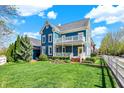 Beautiful two-story blue home with a yellow door and lush green lawn under a bright blue sky with puffy clouds at 12605 Branford St, Carmel, IN 46032