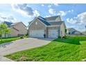 An exterior side view showing the lush green lawn and attached three-car garage at 1662 Cascade Dr, Greenwood, IN 46143