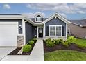 Inviting front entrance with dark siding, white trim, dormer window, manicured front yard and attached garage at 19437 Astoria Ave, Sheridan, IN 46069
