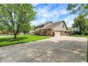 Beautiful home featuring a spacious driveway, well-manicured lawn, and mature trees providing ample shade at 195 Lake Dr, Greenwood, IN 46142