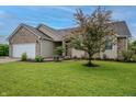 Beautiful single-story home with a well-manicured lawn, lush landscaping, and a tree at 2557 Cedarcrest Dr, Columbus, IN 47203