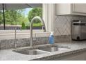 Modern kitchen featuring stainless steel faucet, granite countertops, and herringbone backsplash, perfect for cooking at 601 Ridgeview Ln, Columbus, IN 47201