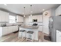 Bright kitchen with white cabinets, a gray center island with seating, stainless steel appliances, and modern pendant lighting at 6164 Brighton Dr, Whitestown, IN 46075