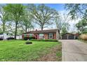 Charming brick home with a detached garage and lengthy driveway, all surrounded by mature trees at 6837 Doris Dr, Indianapolis, IN 46214