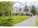 A charming bright white house with beautiful lawn and landscaping, complimented by driveway and US flag at 7950 Westfield Blvd, Indianapolis, IN 46240