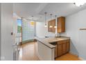 Open-concept kitchen with wood cabinets, gray countertops, glass brick wall feature, and hardwood floors at 920 E 62Nd St # Apt M7, Indianapolis, IN 46220