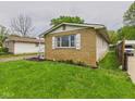 Side exterior view of the brick house showing yard, driveway, and vinyl siding at 979 Monroe St, Indianapolis, IN 46229