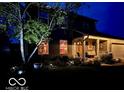 Charming home with warm interior lighting, a cozy front porch, and inviting landscaping at night at 1018 Redwood Dr, Lebanon, IN 46052