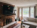 Cozy living room showcasing a brick fireplace with a wooden mantel, natural lighting, and comfy furniture, ideal for relaxing evenings at 106 Walnut St, Southport, IN 46227