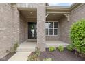Inviting front porch with brick pillars, a black door, and nicely landscaped front yard at 11595 Platt St, Noblesville, IN 46060