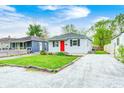 Cozy home with a well-maintained lawn, a stone driveway, and a vibrant red front door at 2021 Reformers Ave, Indianapolis, IN 46203