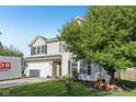 Two-story home with a well-manicured lawn, attached garage, and a beautiful tree with decorative foxes at 2116 Crimson Ln, Lebanon, IN 46052